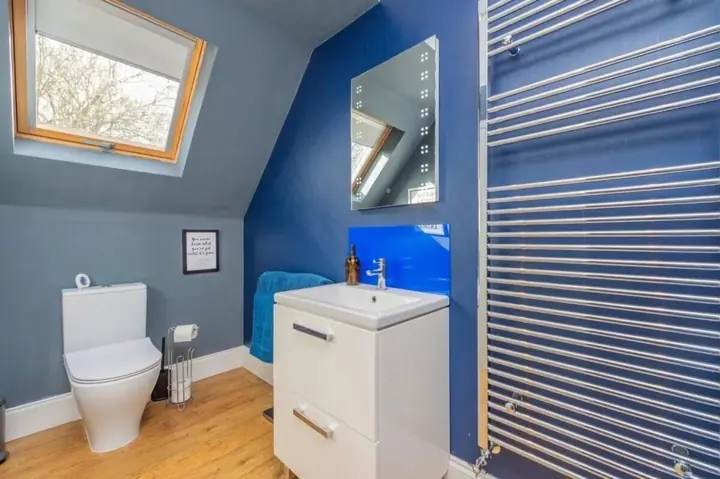 Bathroom with vanity unit, illuminated mirror and skylight