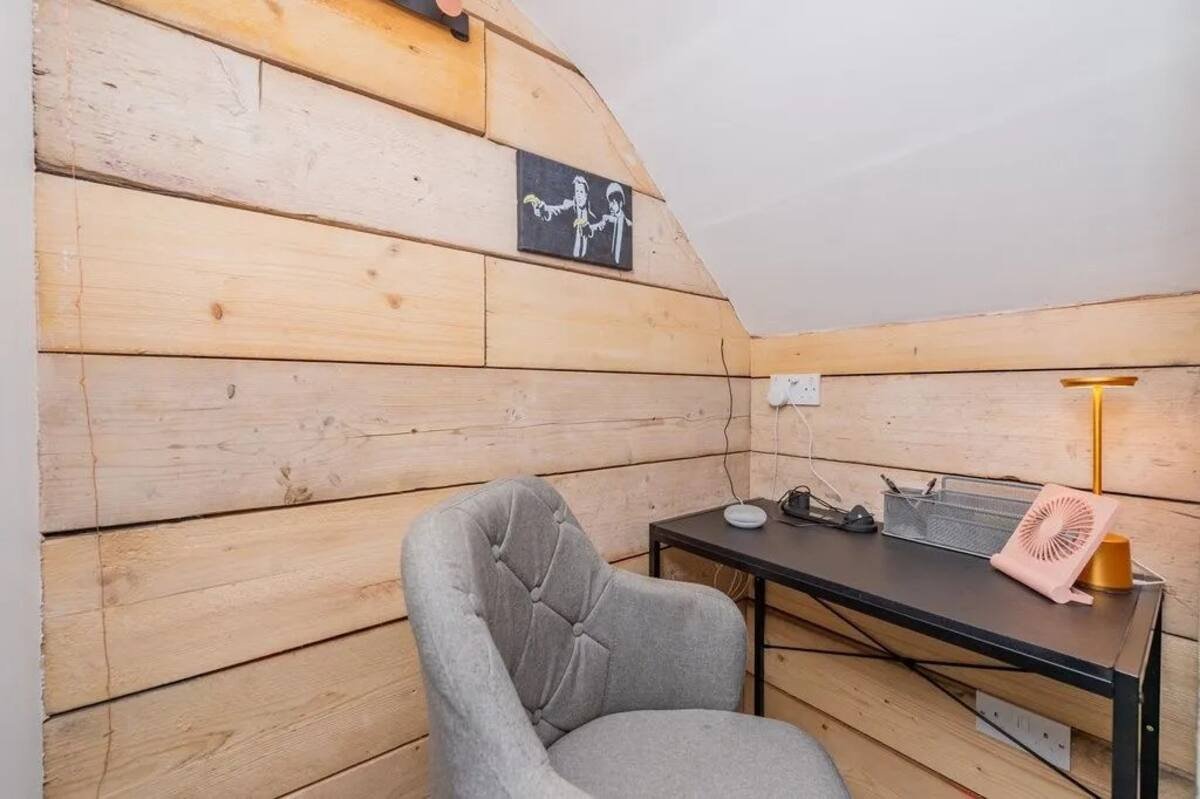 The private desk nook with timber-clad walls, a desk and an upholstered chair